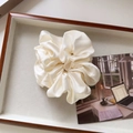 Detailed view of the creamy satin scrunchie with soft silk texture and elegant pleats - Large / Off White