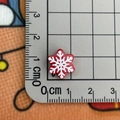 Macro view of a 1.2cm red resin snowflake button with white details on a grid ruler - Snowflake