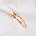 Detailed close-up of a golden magnetic hem buckle with chain on white textured fabric - Gold (6648) / Gold