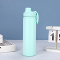 Close-up of a light blue insulated sports bottle with a magnetic cap on a white table - Mint Green