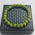 Natural green spotted stone energy bead bracelet displayed on a black textured jewelry box - Bird Egg Pattern Stone Bracelet