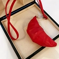 Vue macro d'un mini sac collier rouge en similicuir en forme de croissant en boîte - Rouge