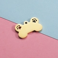 Golden bone-shaped pet pendant with hollow paw prints in titanium steel on pink-blue background - 18K Gold
