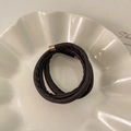 Detail of dark brown leather hair tie with rose gold metal clasp on white ceramic tray - Dark Coffee