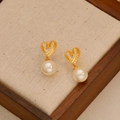 Elegant hollow heart earrings with pearl drops on vintage textured wooden display - 18K Gold (925 Silver Post)