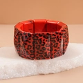 Detailed close-up of a wide red leopard print acrylic bracelet on a white textured stone - Red