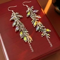 Detailed macro view of colorful crystal fringe tassel earrings on a vintage wood surface - Blue