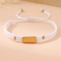 Macro shot of white woven bracelet with a polished gold rectangular metal plate - White (Gold Plate)