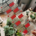 Self-adhesive nail wraps with red hearts and gold glitter patterns shown outdoors - Red Gold Glitter Heart Style (SS-072)