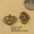 Macro shot of 16x19mm heart bow pendants in antique bronze with a size reference coin - A2437-16*19MM