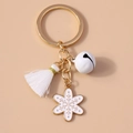 Detail of white tassel keychain with golden snowflake charm and small bell decoration - White Snowflake