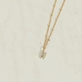 Golden letter H pendant necklace with pearl inlays on a textured white surface - Letter H