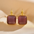 Detailed close-up of gold earrings with square purple gems on beige textured fabric - Coffee Brown