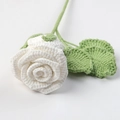 Macro shot of handcrafted white crochet rose with green leaves and detailed yarn texture - Pure White