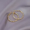 Elegant gold hoop earrings with textured diamond-cut finish on gray silk fabric - E-046---gold 30mm