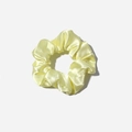 Macro view of silky light yellow satin scrunchie showing smooth pearlescent fabric texture - Bright yellow