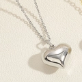 Vista macro de un collar con colgante de corazón 3D plateado con un acabado de espejo liso - Corazón bañado en oro blanco / Plateado