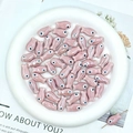 Macro view of pink ceramic fish beads in a white plate for DIY jewelry making - Dusky Pink