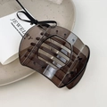 Detailed view of an amber resin hair clip with non-slip teeth on a ceramic tray - Large Gray