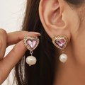 Orecchini a cuore dorati con gemma viola e perle bianche indossati da modella - Pietra preziosa viola / Rosa