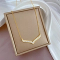 Detail of gold titanium V-shaped necklace with crystals in a brown jewelry box - Gold