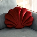 Shell-shaped velvet throw pillow in dark red placed on a modern grey fabric sofa corner - 28x38x10cm / Burgundy