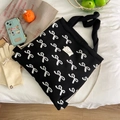 Detailed flat lay of black canvas drawstring bag with white bow pattern and Lady Bug label - Bow Pattern / Black and White Bow