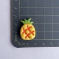 Detail shot of a yellow resin pineapple charm showing precise 2.5cm size on a black scale - Yellow Pineapple