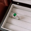 Detailed macro view of an emerald green oval zircon ring in a gray jewelry box - Silver Base Green Oval Style
