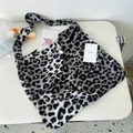 Detail view of large leopard print tote bag with a woven MISS tag on side seam - Grey Leopard