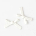 Detailed macro view of two white alloy bow-shaped beads for DIY jewelry making - White