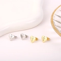 Gedetailleerd close-up van zilveren en gouden hart oorbellen met glinsterende letter T. - Letter T