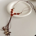 Détail d'un collier bohème avec perles en bois marron et pendentif à pompon - Marron