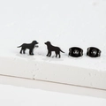 Macro shot of minimalist black dog silhouette stud earrings on a textured stone surface - Dog / Black