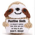 Macro shot of handmade crochet sloth holding a card with positive inspirational quote - Otter