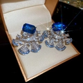 Macro shot of silver fan-shaped earrings with blue gemstones and sparkling diamonds - Blue (925 Silver Pin)