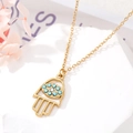 Détail du pendentif main de Hamsa doré avec pierres bleues et zircon sur socle marbre - Style 6 Main de Fatima Ajourée avec Zircone Bleue