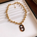 Collana a sfere in acciaio dorato con ciondolo ovale traforato in acetato ambrato - Design con Fibbia a Naso di Maiale Ovale (Motivo Tartarugato)