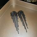Close-up of black teardrop tassel earrings with sparkling rhinestones on a gold tray - V-Shape Tassel Style (12# Gun Black Silver Needle)