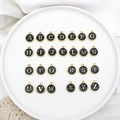 Detailed view of 26 black and gold alloy alphabet charms arranged on a white ceramic plate - Letter A / 1#Black Letter