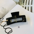 Glossy black rectangular hair claw clip for women shown on a minimalist magazine backdrop - Glossy Black