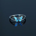 Leuchtender blauer Schmetterlingsring aus Edelstahl mit Spiegelung auf dunklem Grund - US 8 / NY799 Kleiner Schmetterling