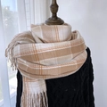 Beige and white plaid scarf with fringe detail on a black knit background - Khaki