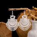 Detailed view of silver ethnic earrings with hollow carving and droplet tassels on wood - 3-Layer Silver Phoenix