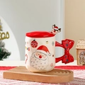 Dettaglio di una tazza natalizia in ceramica con manico a fiocco rosso e tappo a renna - Babbo Natale