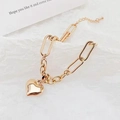 Golden titanium steel link bracelet with bold heart pendant on white textured background - Rose Gold