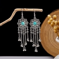 Macro shot of silver bohemian tassel earrings with turquoise stones on a branch - E2870-9 (Antique Silver Teal Tassel)