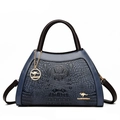 Elegant navy blue crocodile pattern handbag with dark brown handles and gold logo accents - Blue
