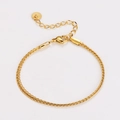Dettaglio di un bracciale dorato a maglia intrecciata con chiusura regolabile e piastrina - Oro