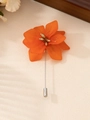 Dettaglio macro di un'elegante spilla a fiore arancione con petali in resina e spilla argento - Rosso Arancio